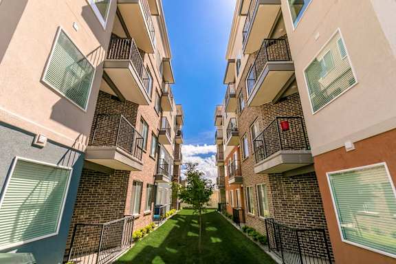 A row of apartment buildings with balconies and a green lawn in the foreground.