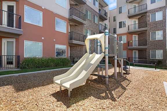 A playground with a slide in front of apartment buildings.