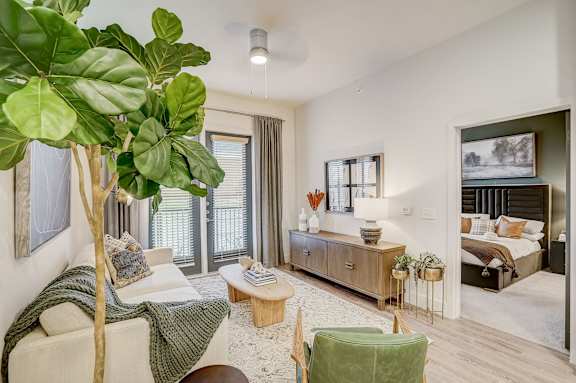 a living room with a large plant and a bedroom with a bed at The Mill Old Town, Lewisville, TX, 75057