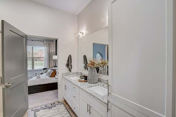 a bathroom with a sink and a mirror and a door to a bedroom at The Mill Old Town, Texas, 75057