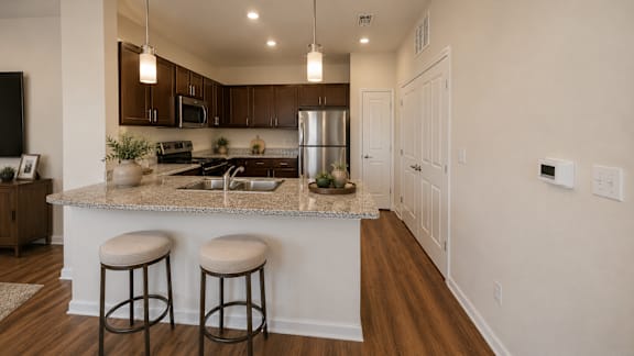Modern apartment kitchen with granite-style countertops, bar seating, and stainless steel appliances at Auberge of Tyler.