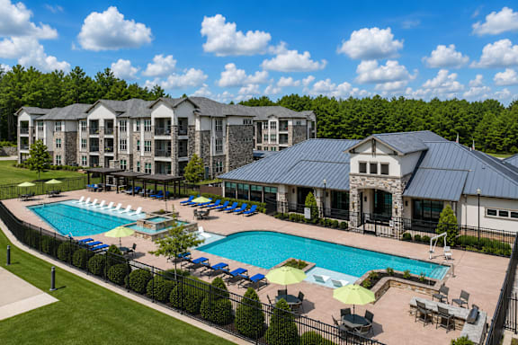 Resort-style swimming pool surrounded by apartment homes and lounge seating at Auberge of Tyler.