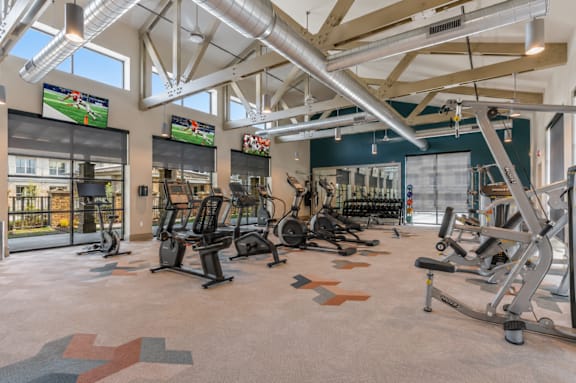 A gym with a variety of equipment including treadmills, weights, and exercise machines.