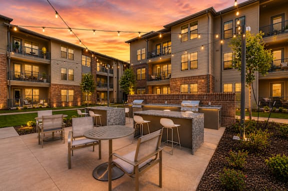 Outdoor grilling station and resident courtyard illuminated at sunset at One Preston Station Apartments.