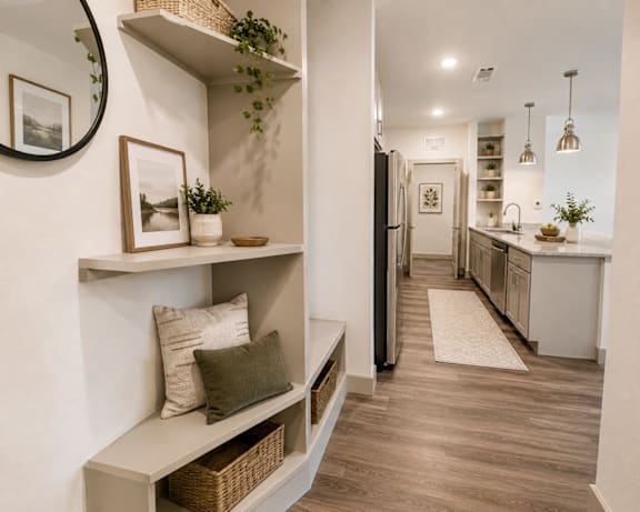 A kitchen with a refrigerator, a counter, and a shelf with a potted plant on it.