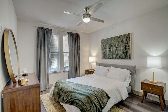 A bedroom with a bed, nightstand, and a mirror.
