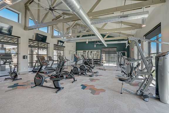 A gym with a variety of exercise equipment including treadmills, stationary bikes, and weight machines.