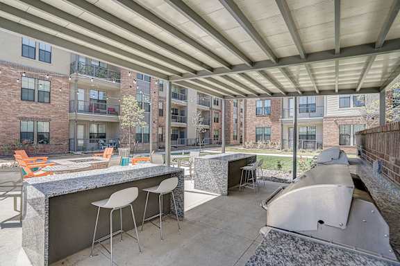 A patio with a bar and chairs is covered by a roof.