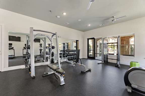A spacious gym with a variety of equipment including a squat rack, bench, and weights.