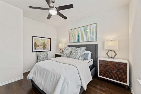 A bedroom with a bed, nightstand, and a ceiling fan.