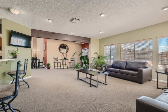 Clubhouse with a couch, chairs, and a television at Horizon East Apartments in Aurora, CO.