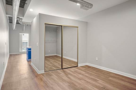 a room with a mirrored closet door and a hard wood floor at Sleek Lofts Denver CO