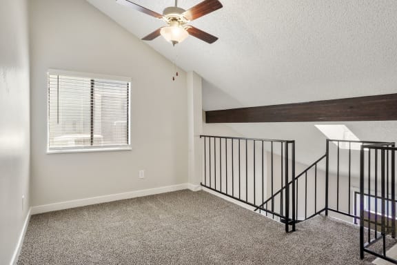 a loft in a home with a ceiling fan and a window  at Hilltop View in Denver, CO