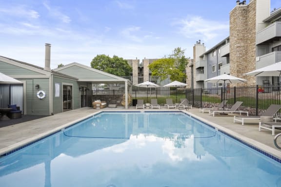 a swimming pool with lounge chairs and umbrellas in front of a building