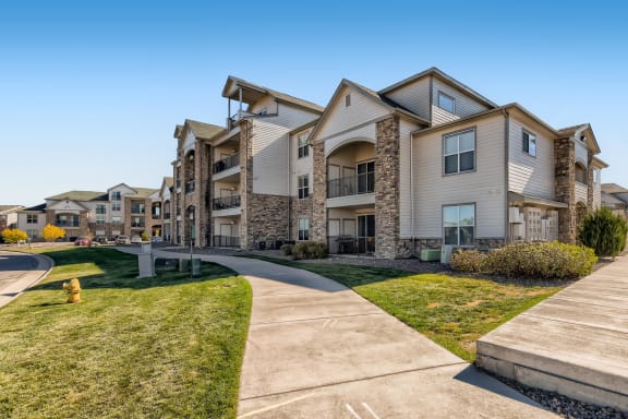 A large, modern apartment complex with a well-maintained lawn and a clear sky at Fox Run Lofts Apartments, Englewood Colorado.