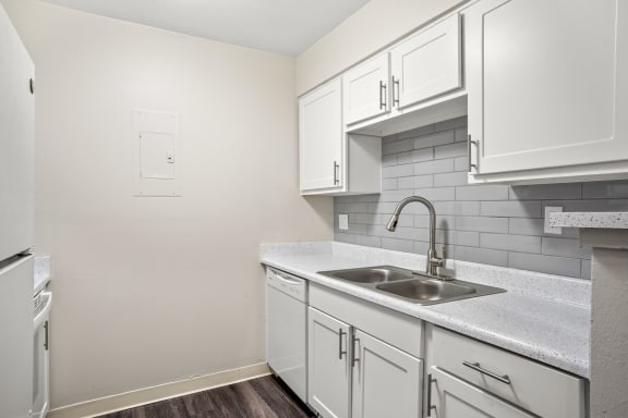 a kitchen with white cabinets and a stainless steel sink and dishwasher  at Hilltop View in Denver, CO