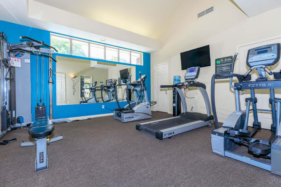 A gym with a variety of equipment including treadmills, weights, and exercise machines  at The Buttes Apartments Loveland, CO.