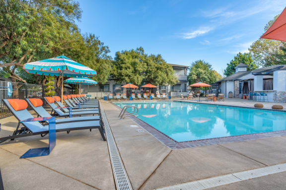 our resort style pool is filled with lounge chairs and umbrellas