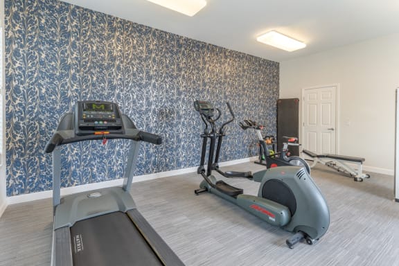 a gym with exercise equipment and blue wallpaper on the wall