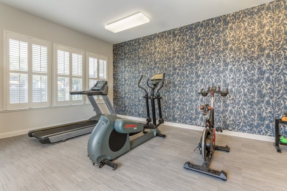 a gym with exercise equipment and blue wallpaper