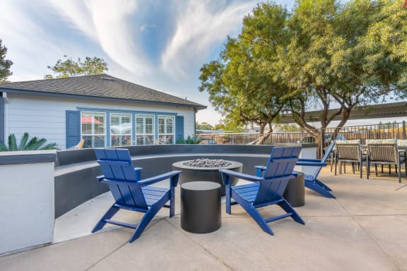 a patio with blue chairs and a fire pit     and a building