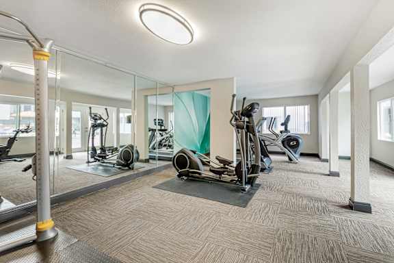 a gym with treadmills and other exercise equipment in a building with glass walls