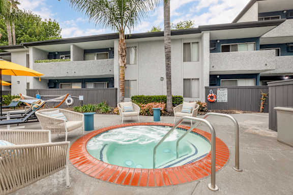 a hot tub with chairs and a palm tree in front of a building
