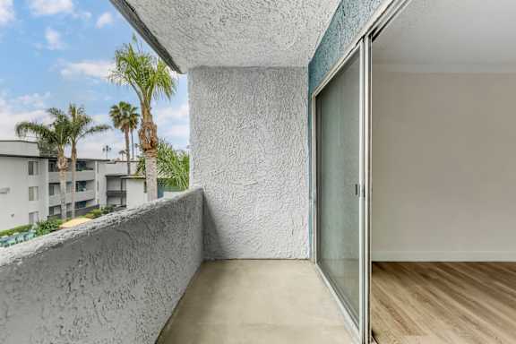 a balcony with a sliding glass door and a patio with palm trees