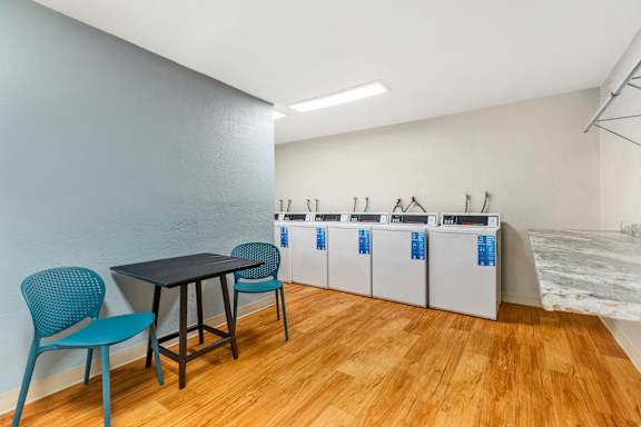 a room with a table and chairs and a laundry room with washing machines
