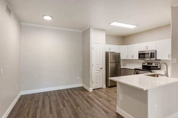 an empty kitchen with white cabinets and a stainless steel refrigerator at Trevi Apartment Homes, Chandler, Arizona