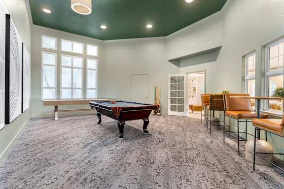 A room with a pool table and a bench.
