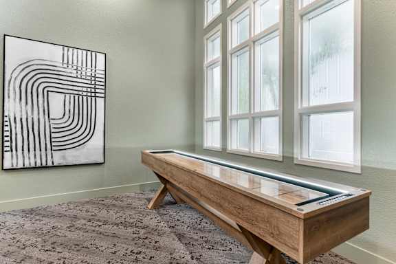 A black and white abstract painting hangs on a wall above a wooden table with a drawer.