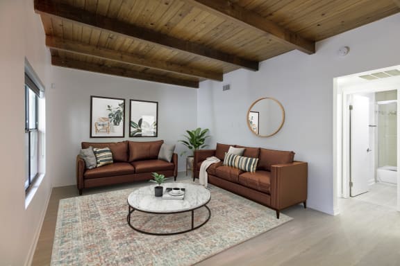a living room with two brown couches and a round coffee table