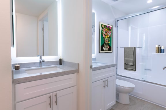 a bathroom with white cabinets and a white toilet next to a white sink and shower