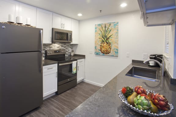 a kitchen with white cabinets and stainless steel appliances and a bowl of fruit on the counter at Club Pacifica, Benicia