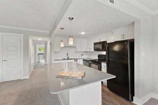 a kitchen with a large island and a black refrigerator