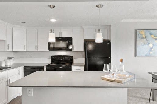 a kitchen with white cabinets and a black refrigerator