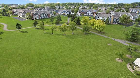 an aerial view of a green lawn with houses in the background