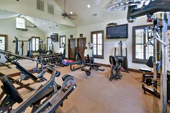 spacious gym with cardio equipment and a flat screen tv