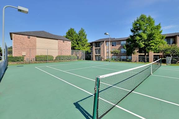 A tennis court with a net and a building in the background.