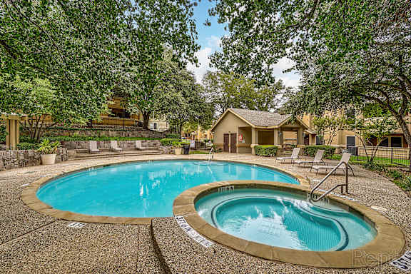A swimming pool surrounded by trees and a house in the background.