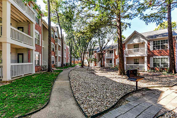 A residential area with apartment buildings and a pebble-covered pathway.