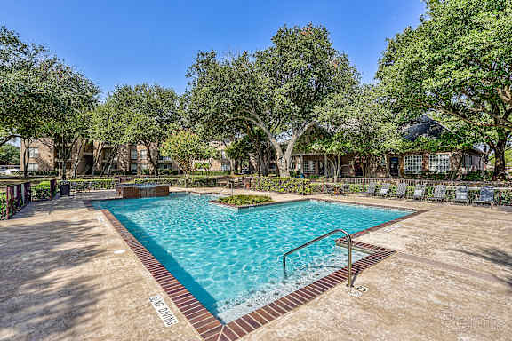 A large outdoor pool surrounded by trees and a fence.