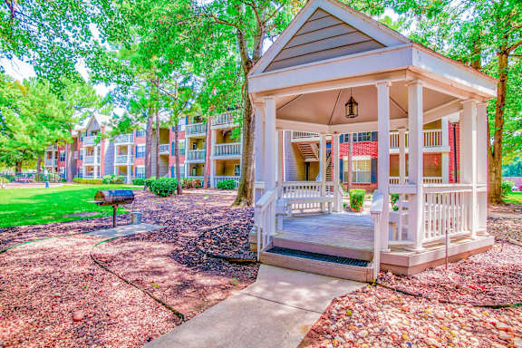 A gazebo is in the middle of a grassy area with apartment buildings in the background at Greenbriar Apartments, Tulsa, OK