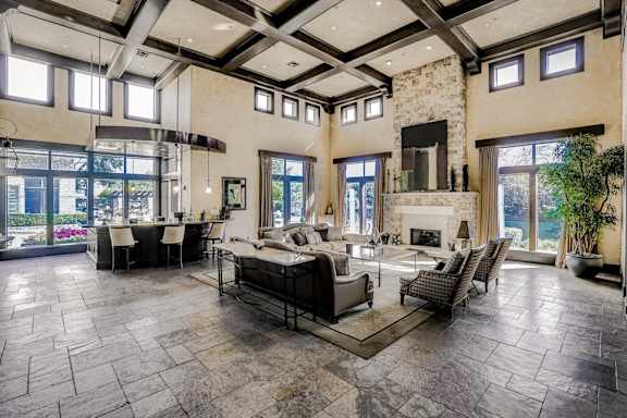 A large, open-concept living room with a stone fireplace and a stone floor at Cypress Lake at Stonebriar Apartments, Frisco Texas
