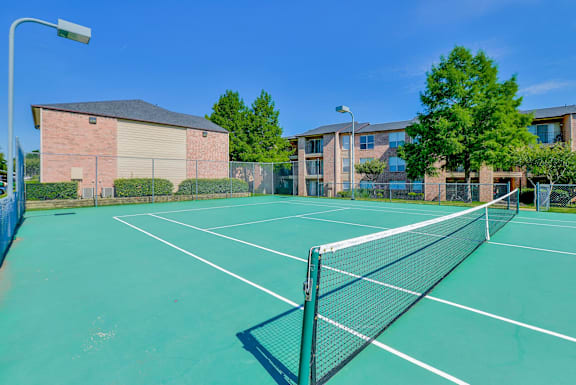A tennis court with a green surface and a white net.