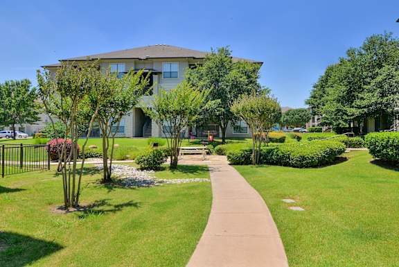 A building with a green lawn in front of it at Cypress Lake at Stonebriar Apartments, Frisco, TX 75034