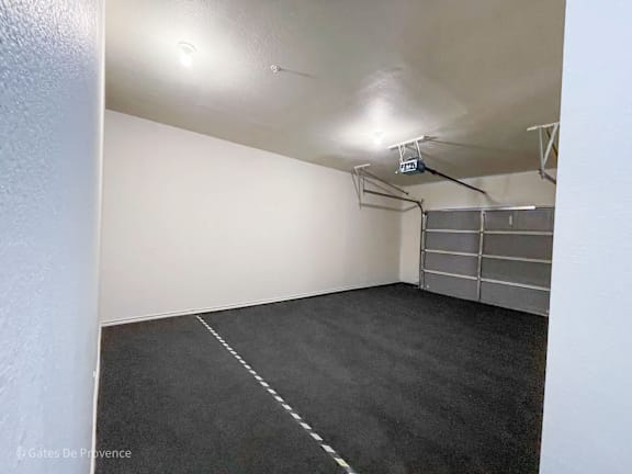 A sparsely furnished room with a white wall and a grey carpet.