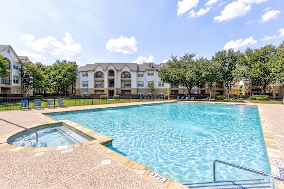 A large swimming pool in front of apartment buildings.