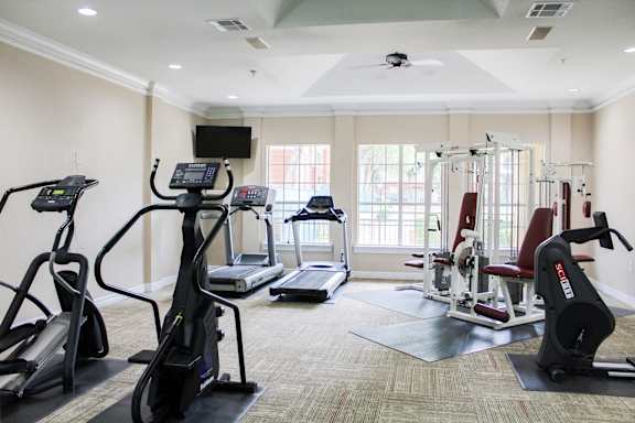 a gym with cardio equipment and a window
